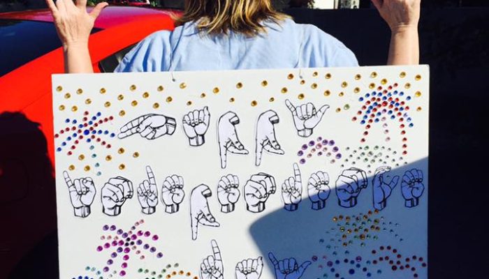 person carrying sign of hands in position for the abcs of american sign language