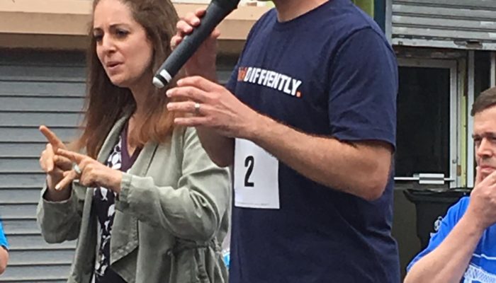 sign language interpreter signing for person speaking into microphone