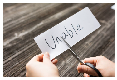 the word unable with someone cutting the paper between the letters un and able