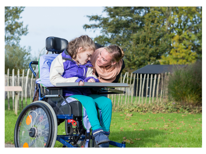 a woman smiling with a child in a wheelchair